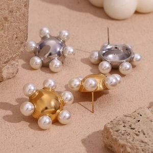Macro detail of 18K gold and silver plated wheel stud earrings with pearl inlay accents