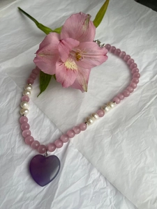 Detail of pink cat-eye beads and white pearls with a purple heart pendant necklace