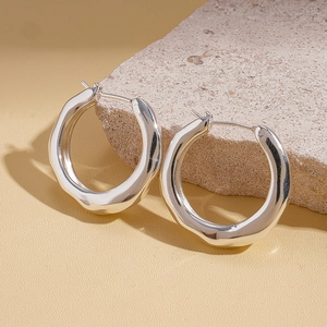 Detailed close-up of silver geometric crumpled earrings on a natural stone base