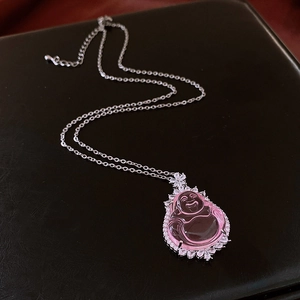 Detail view of pink Buddha pendant with white zircon inlay on black leather background