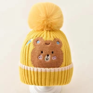 Bright yellow knit baby hat with cute bear embroidery and a large fluffy pompom