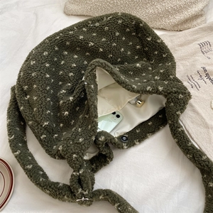 Detail view of plush green faux shearling tote bag with white dots and magnetic closure