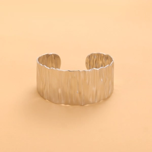 Macro detail of silver titanium steel open bangle with unique hammered metal texture