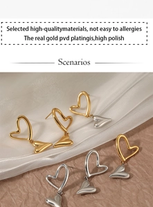 Macro detail of high-polished gold and silver heart earrings with PVD plating