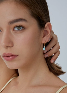 Close-up of elegant gold-plated hoop earrings with sky blue pendants and zircon stones