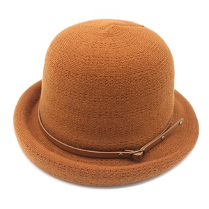 Détail d'un chapeau cloche en maille caramel avec sangle décorative en cuir et boucle métal