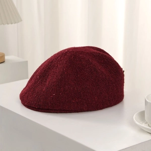 Detailed knit texture of burgundy newsboy cap with subtle shimmering sequins accents