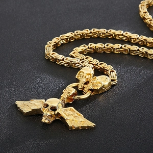 Close-up of golden skull pendant with wings and Byzantine chain for men