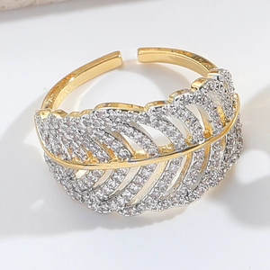 Macro detail of a gold feather open ring featuring pavé set sparkling zirconia stones
