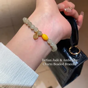 Bracelet en jade Hetian avec perle d'ambre et pendentif porte-bonheur doré au poignet
