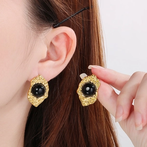 Detailed close-up of vintage 18K gold plated earrings with black cat-eye stone on the ear