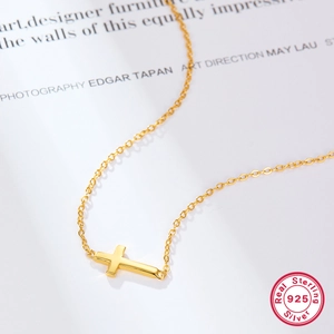 Polished S925 sterling silver gold-plated cross pendant necklace on an art magazine