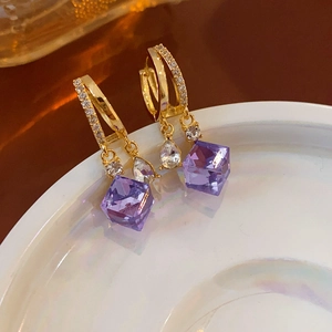 Detail of gold-plated earrings featuring double hoops and sparkling purple crystal cubes