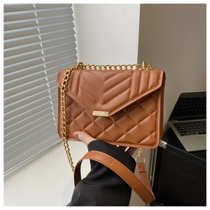 Detail of brown quilted leather bag with V-shaped stitching and gold chain strap