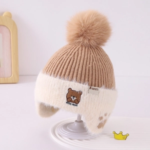 Detail of baby winter knit hat featuring cute bear patch and soft pompom decor