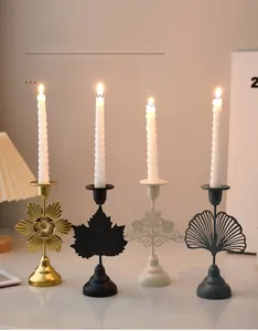 Close-up of four iron art candlesticks in gold, black, and grey with spiral candles