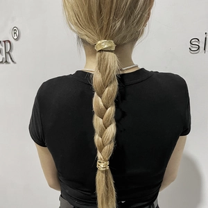 Detailed view of golden metal ponytail cuff with textured wire on braided hair