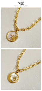 Detail view of gold necklaces with sun and moon pendants on mother of pearl and marble