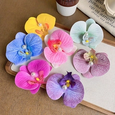 Detailed view of colorful orchid hair accessories with pearl centers on a white tray
