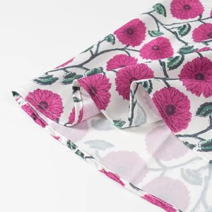 Gros plan sur un tissu mousseline blanc avec imprimé floral rose et coutures de l'ourlet