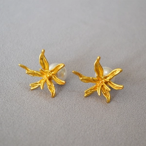 Detailed close-up of vintage flower earrings featuring brass plating and a central white pearl