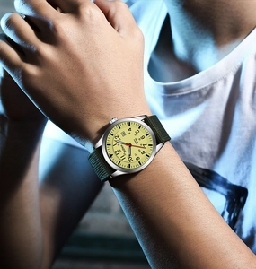 Detail of military quartz watch with army green nylon strap and date window on wrist