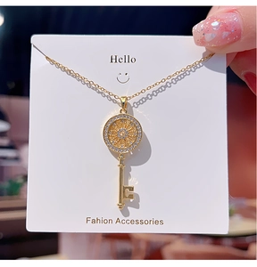 Macro shot of a golden key pendant with cubic zirconia inlay on a display card