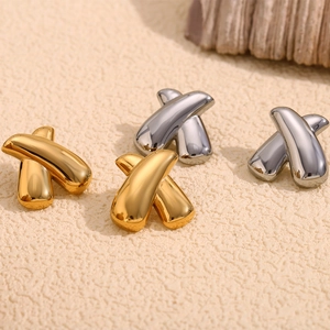 Macro detail of geometric X-shaped stud earrings in polished gold and silver finishes