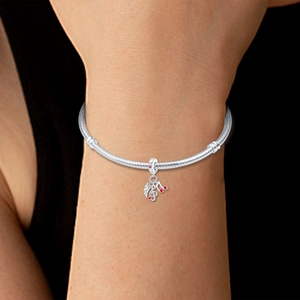 Detailed close-up of 925 silver musical note and feather charms on a snake chain bracelet
