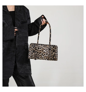 Detail of leopard print handbag with leather strap shown on black textured suit