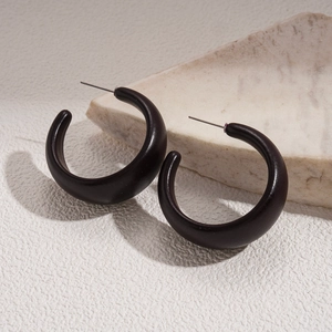 Macro shot of dark brown C-shaped acrylic hoop earrings with matte resin texture