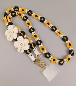 Detail of hand-woven phone lanyard with sunflower patterns and white smile charms