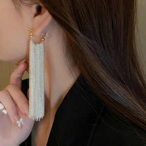 Close-up of elegant long silver chain tassels and gold spherical stud earrings on model