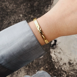Detailed view of irregular lunar hammer texture on gold-plated stainless steel cuff bracelet