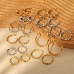 Chic twisted 18K gold and silver hoop earrings in various sizes on a rustic wooden backdrop