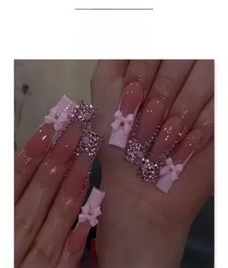 Macro view of French long square nails with pink rhinestones and 3D bow design