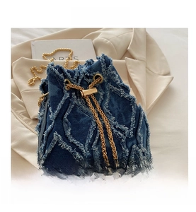 Close-up of denim bucket bag featuring frayed quilting and gold pearl chain detail