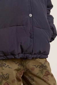 Detail of navy blue quilted puffer jacket with branded snap buttons and drawstring hem