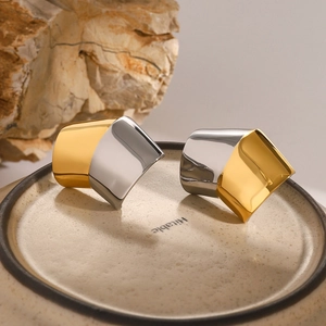 Detail of two-tone gold and silver geometric earrings on ceramic tray with stone