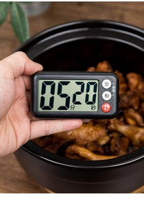 Close-up of a black kitchen timer with large LCD screen held over a cooking pot