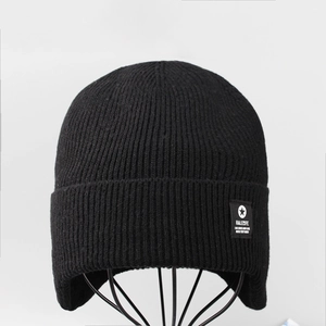 Close-up of black ribbed knit winter beanie featuring a star patch and warm ear flaps
