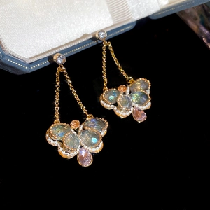 Detail of crystal butterfly earrings with pink teardrop stones on black velvet