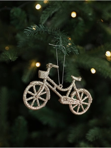 Close-up of golden glitter bicycle ornament hanging on a Christmas tree branch