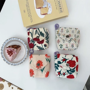 Detailed macro view of four mini floral fabric pouches with metal snaps and purple loops