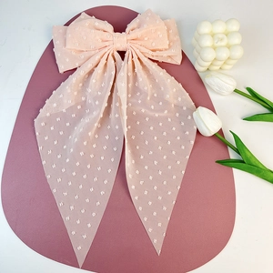 Close-up of pink chiffon hair bow clip with white 3D polka dots and long flowing ribbons