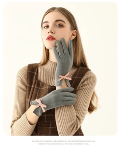 Détail de gants thermiques gris avec nœud rose portés par un mannequin en studio