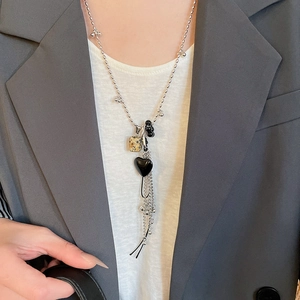 Dettaglio di una collana lunga con perline, cuore nero, pietra quadrata e nappe d'argento