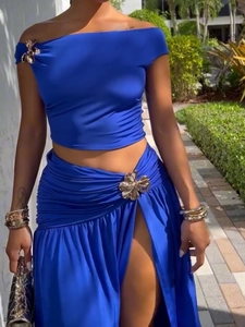 Detail of royal blue two-piece set featuring gold floral buckles and a high slit skirt