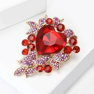 Macro shot of luxury gold brooch with large red heart gem and iridescent rhinestones