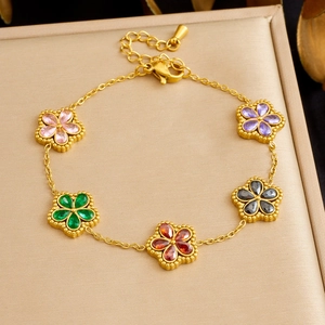 Macro di un bracciale placcato oro con cinque ciondoli a fiore in pietre colorate